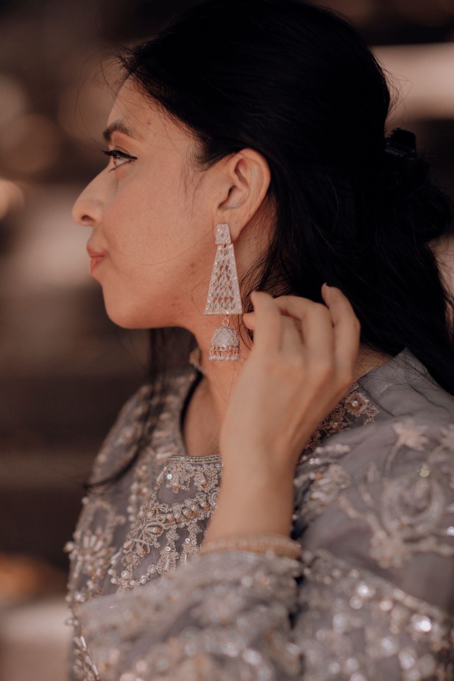 Woman in elegant light traditional Indian clothing wearing ornate earrings