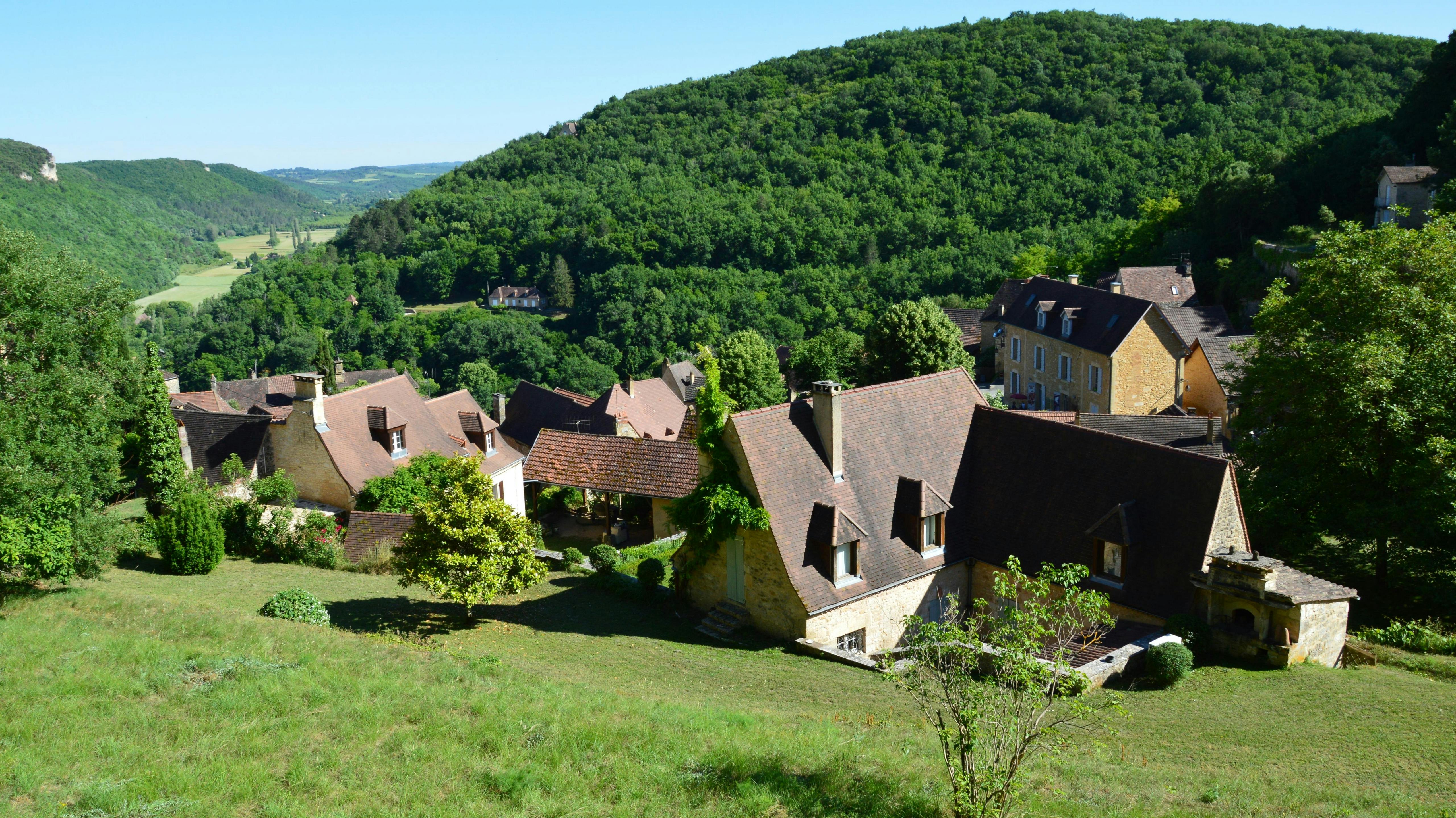 A picturesque aerial view of a quaint village surrounded by lush green hills.