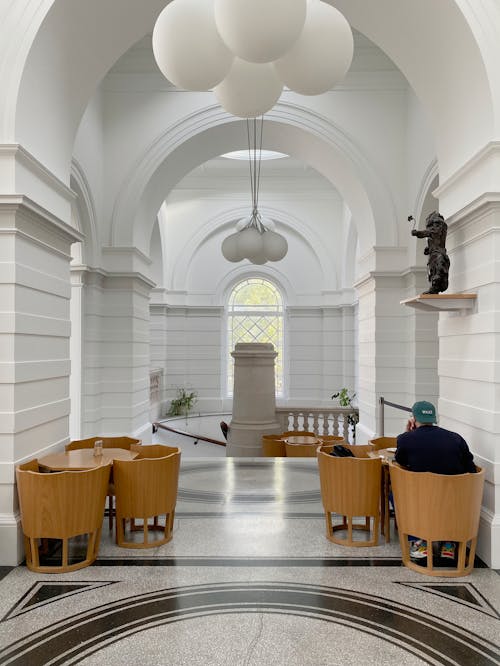 A Person Sitting on Brown Wooden Chair Inside a Building