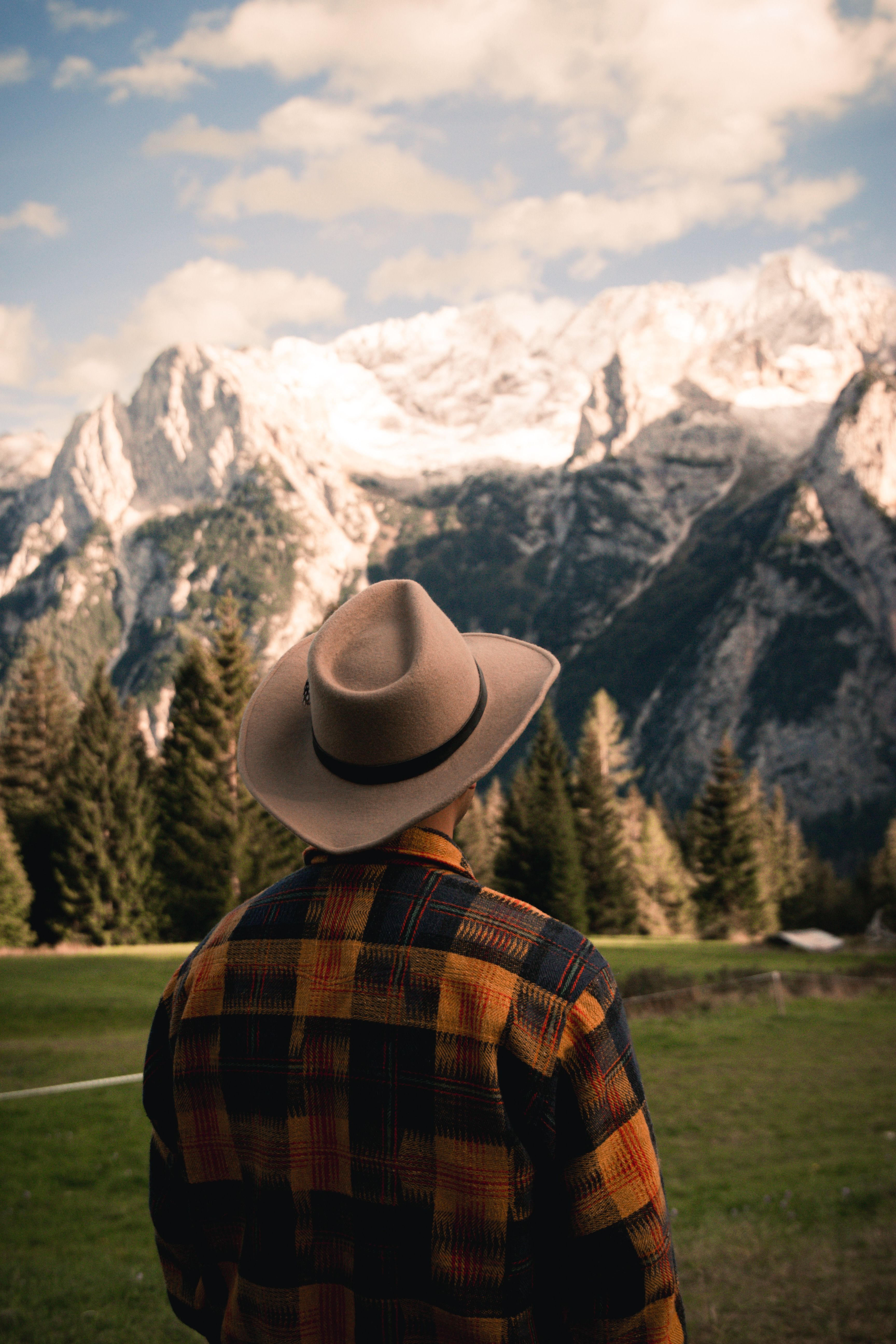A man in a checkered shirt and hat enjoys the scenic mountain view in Trentino-South Tyrol, Italy.