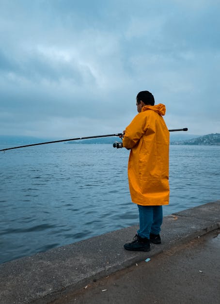 Cheerful boy wearing raincoat holding fishing net Stock Photo - Alamy