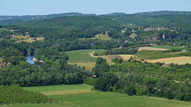 Picturesque aerial view of lush green hills and a winding river in a summer landscape.