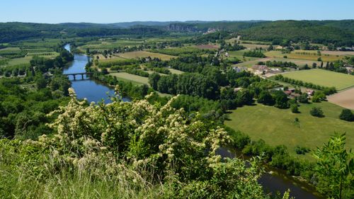 Free Scenic view of lush countryside with river, fields, and bridge under a clear blue sky. Stock Photo