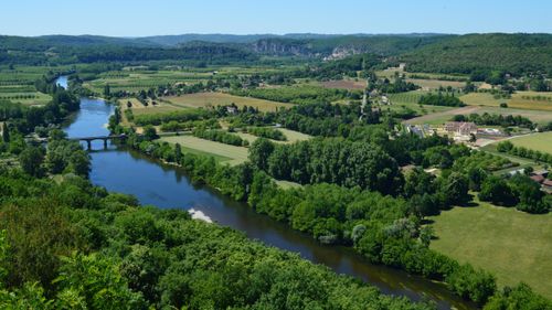 Free A picturesque aerial view of a river meandering through lush green fields and forests. Stock Photo