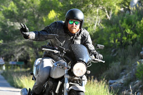 Free Man Riding a Motorcycle doing a Peace Sign Stock Photo