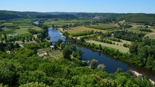Free Beautiful aerial view of a lush countryside with a winding river and expansive greenery on a summer day. Stock Photo