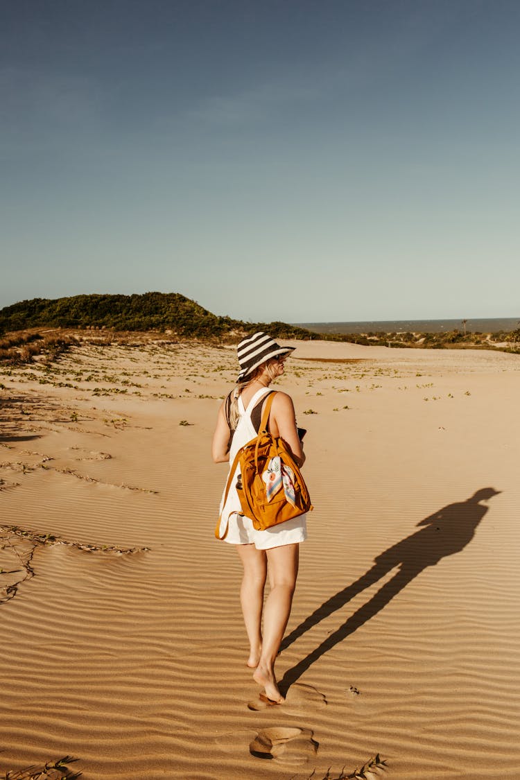 Woman Wearing Backpack Walking On Sand