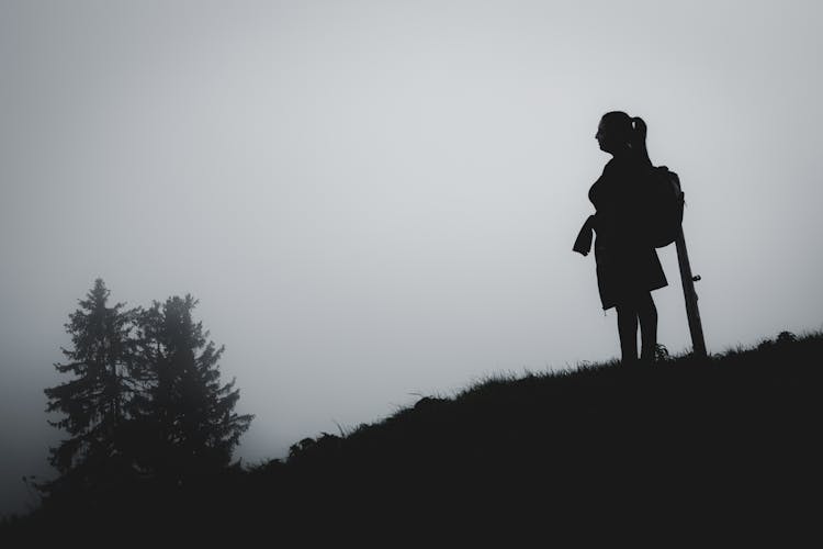 Silhouette Of Woman With Backpack Standing On Mountain Hill