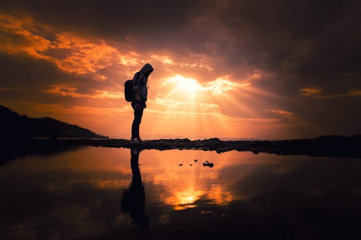 在土耳其科尔根反光的湖面上，一名孤独的徒步旅行者的身影在充满活力的日落映衬下被勾勒出来