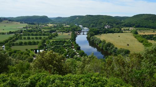 Free A picturesque aerial view of lush green countryside with a winding river and distant hills in summer. Stock Photo