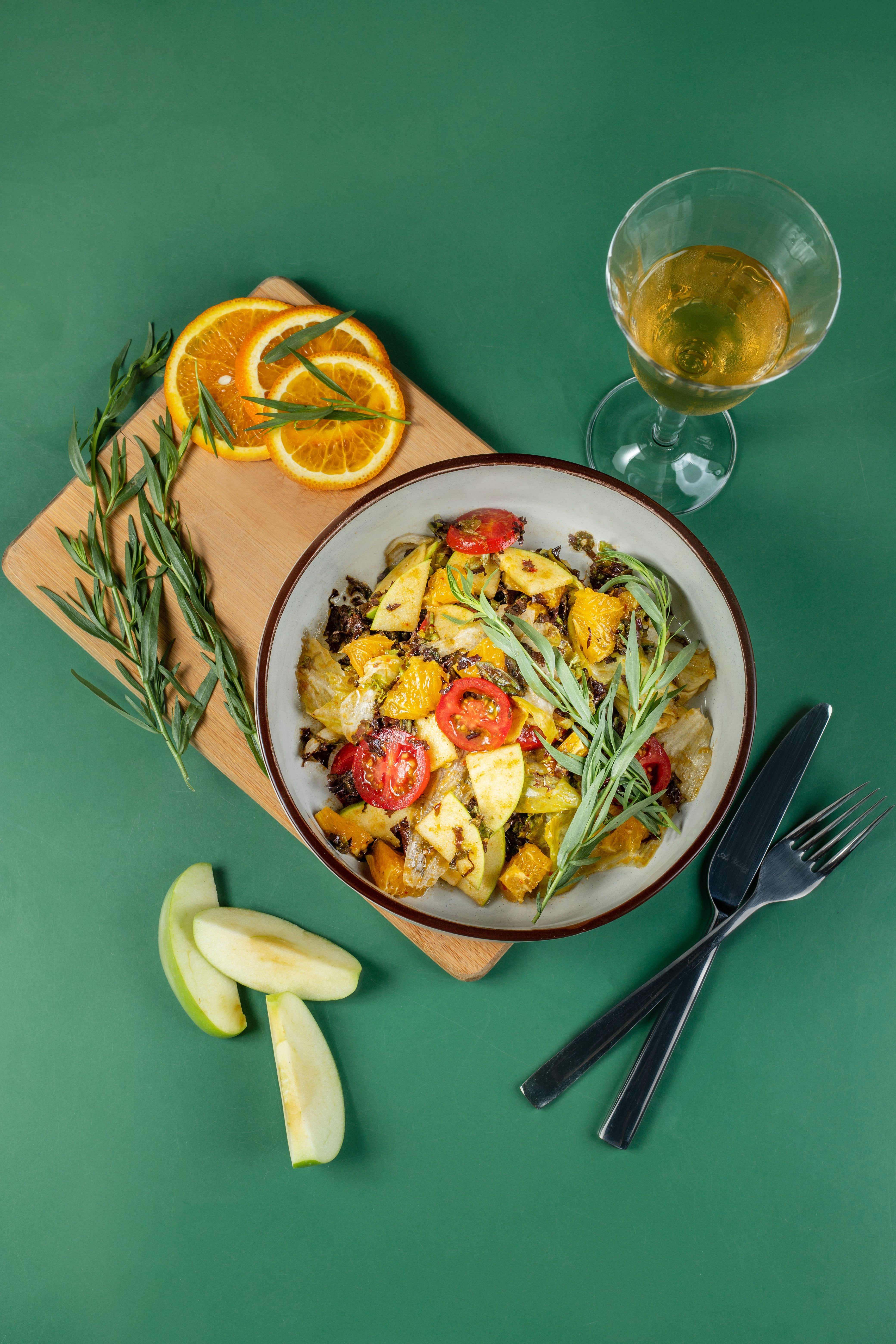 Top view of a vibrant vegetable salad with citrus slices on a green background.