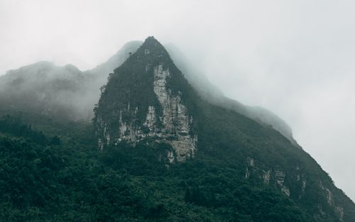 Free Dramatic view of a foggy mountain peak covered in lush green forest. Stock Photo