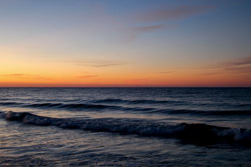 Free Tranquil ocean view at twilight with gentle waves and colorful horizon. Stock Photo