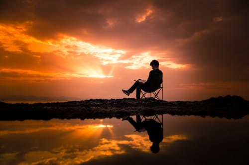 무료 새벽 동안 캠핑 의자에 앉아있는 남자의 사진 스톡 사진