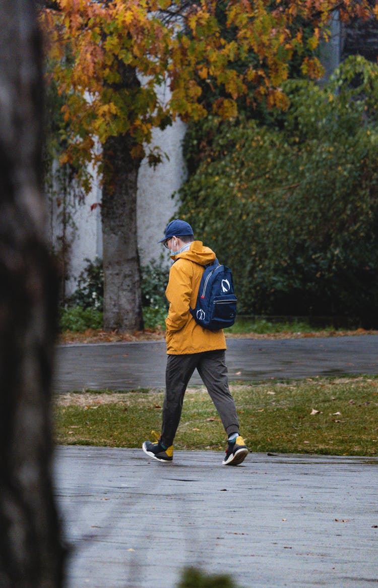 A Man In A Yellow Hoodie Walking On A Street