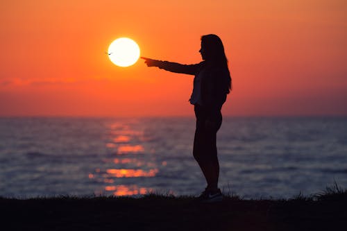 夜明けの間に太陽を横切る女性