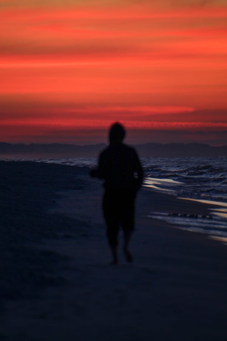 Silhouette Of Man Running On The Beach