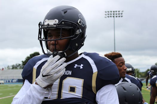 Football players in full gear preparing for a game on the field under cloudy skies.