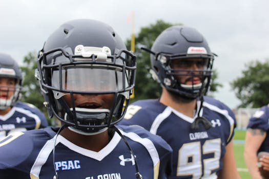 Close-up of American football players in action, wearing helmets and jerseys, showcasing team spirit.