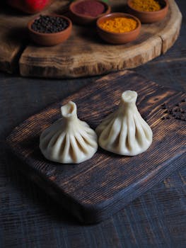 Close-up of traditional dumplings on a wooden board with spices, enhancing culinary allure.