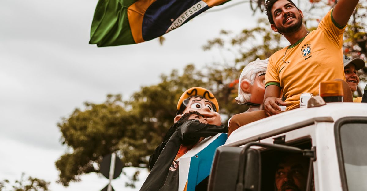 Grupo de pessoas segurando bandeira do Brasil em caminhão durante manifestação
