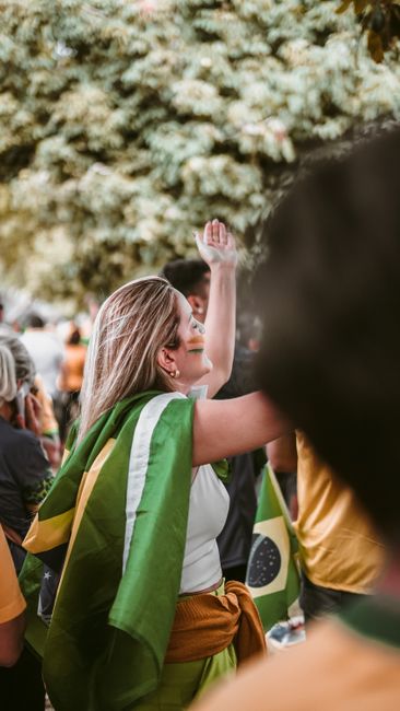 Fotomural Una animada celebración en la calle con personas agitando banderas brasileñas con alegría al aire libre.