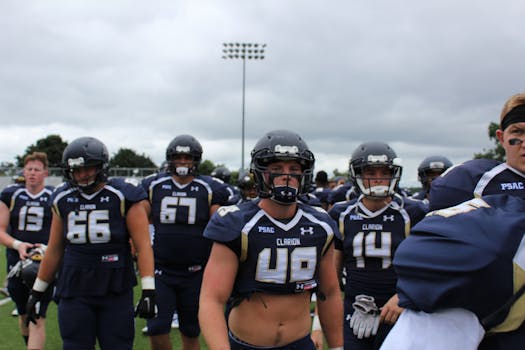 American football players in uniform and helmets getting ready for a game on a cloudy day.