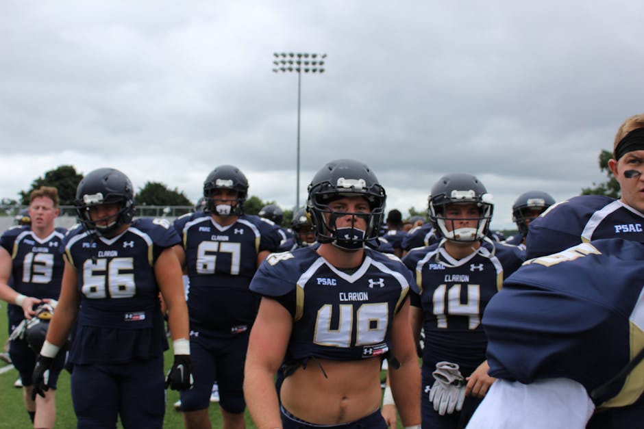 American football players in uniform and helmets getting ready for a game on a cloudy day.