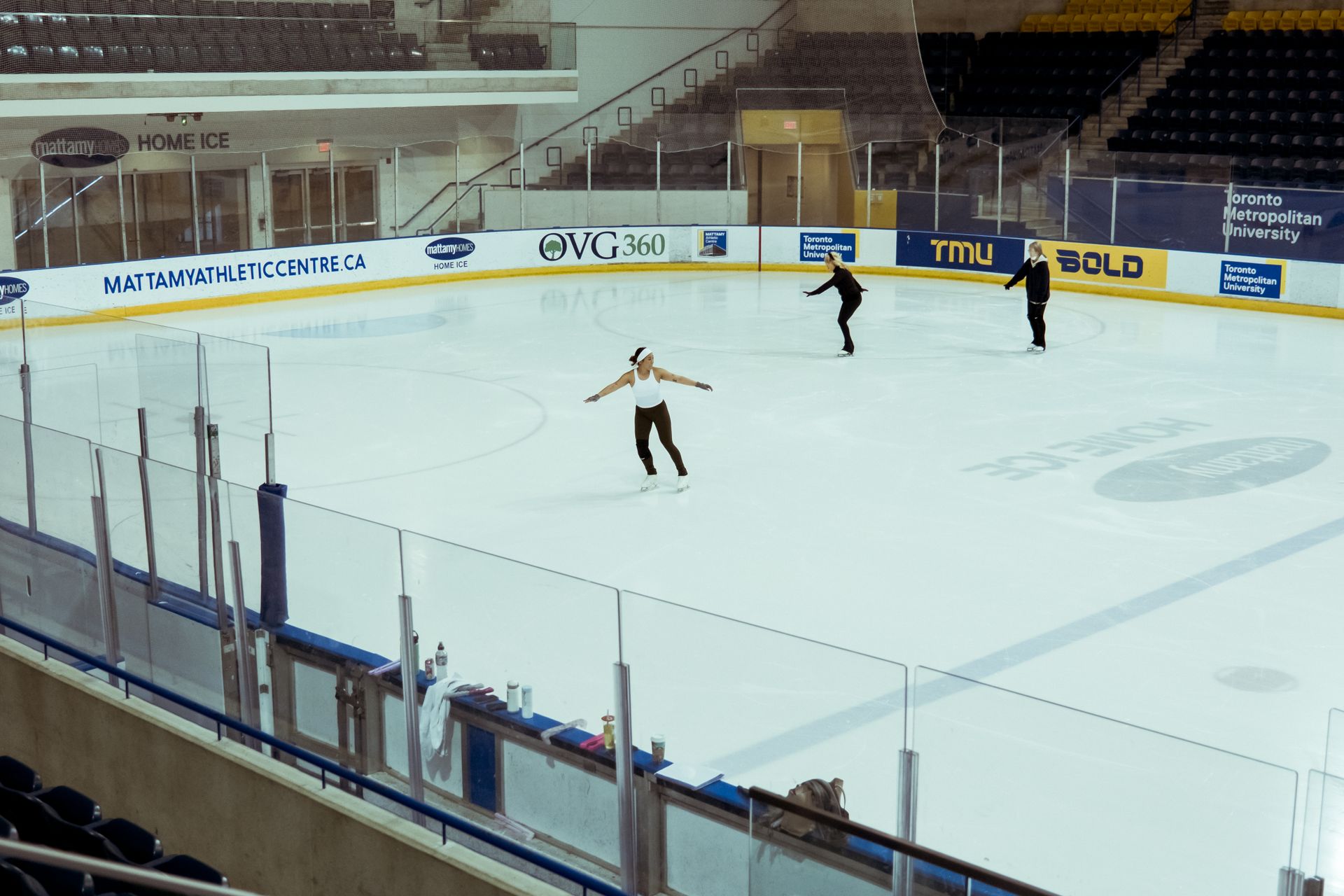 Figure skaters practicing at an indoor ice rink in Toronto Metropolitan University.