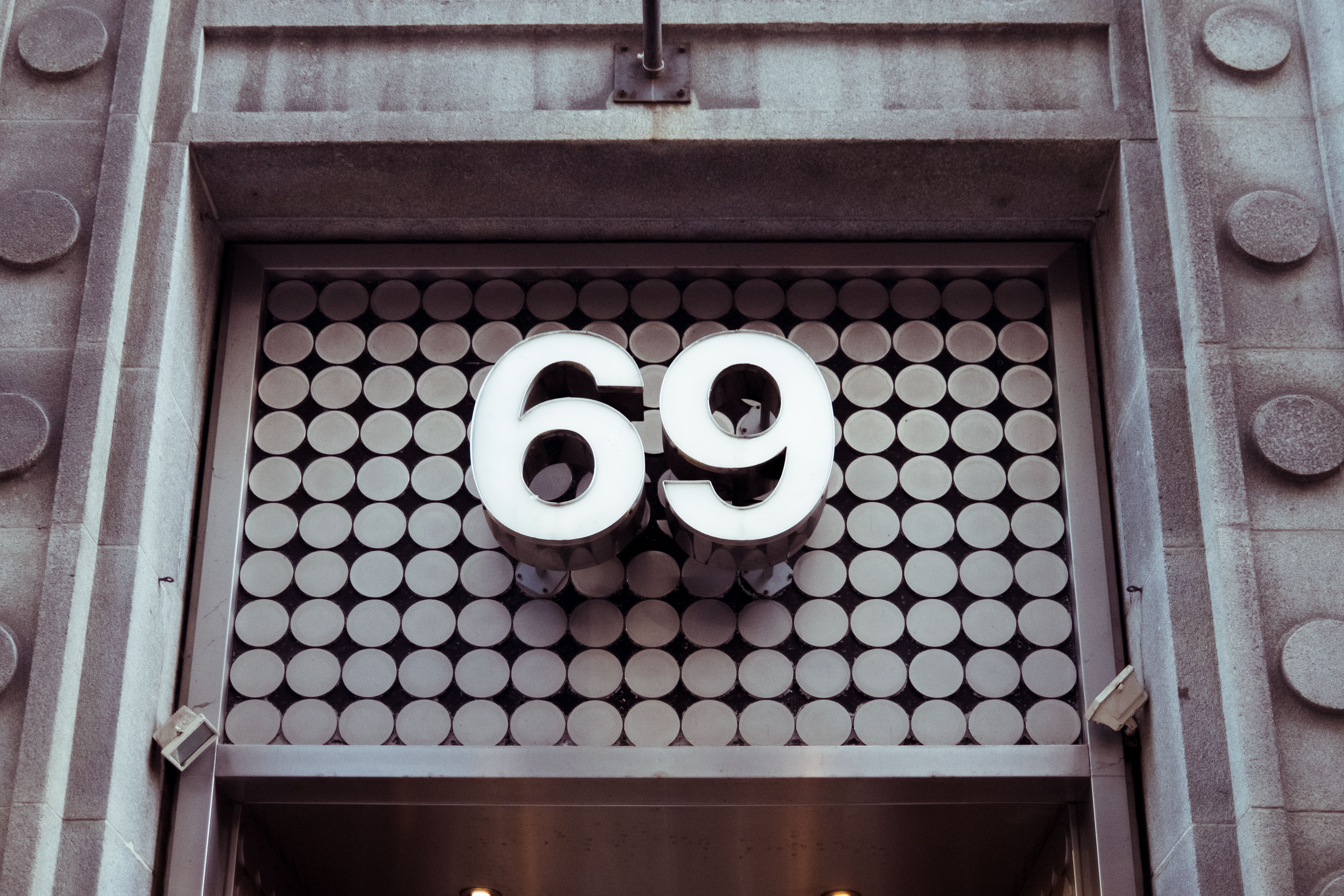 Close-up of a modern building facade featuring a geometric design and prominent number 69.
