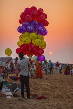 Colorful balloons and lively crowd at sunset on Puri Beach, India.