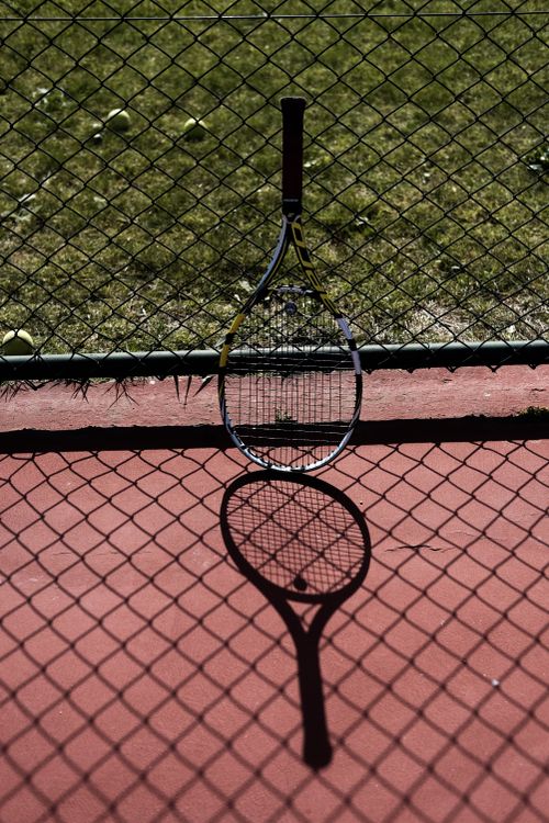 A Tennis Racket Leaning on a Wire Mesh Fence · Free Stock Photo