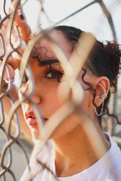 A Woman Leaning on a Wire Mesh Fence