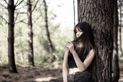 Woman in Black Tank Top leaning on a Tree