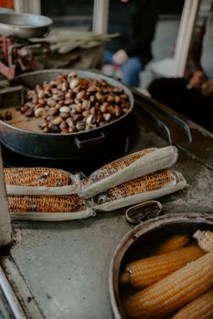 A street vendor's setup with grilled corn cobs and roasted chestnuts, showcasing traditional food preparation.