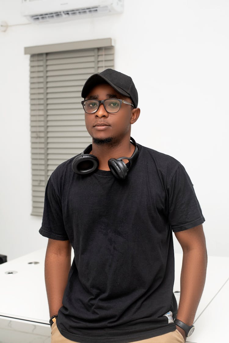 A Portrait Of A Man In A Black Shirt And A Cap