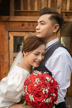 Bride and groom sharing a joyful embrace with a beautiful bouquet of red roses.