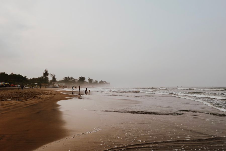 A tranquil sandy beach with gentle waves under a cloudy sky, perfect for relaxation.