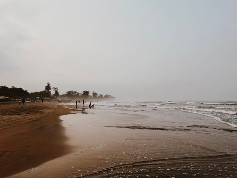 A tranquil sandy beach with gentle waves under a cloudy sky, perfect for relaxation.
