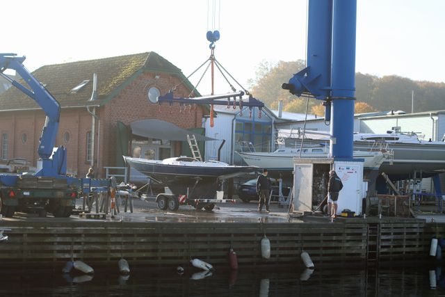 Bateau soulevé pour maintenance dans un port avec bâtiments industriels