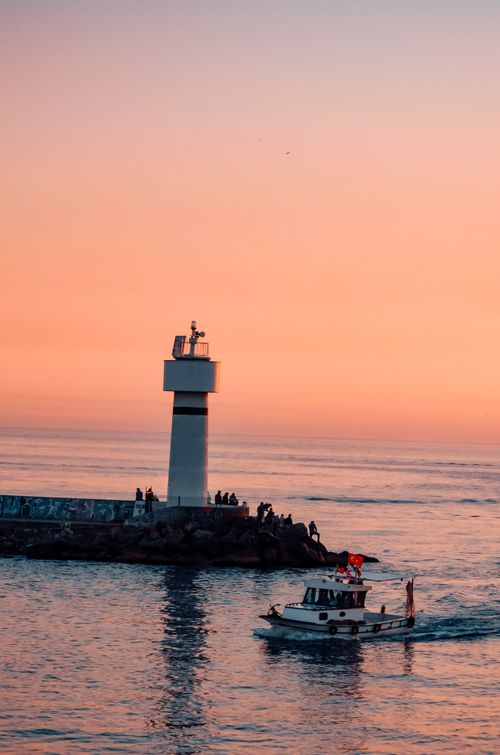 Free A picturesque view of a lighthouse and boat during a vibrant Istanbul sunset over the sea. Stock Photo