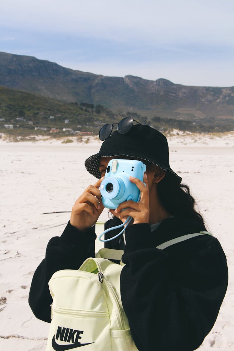 Photo Of A Woman Using A Blue Polaroid Camera