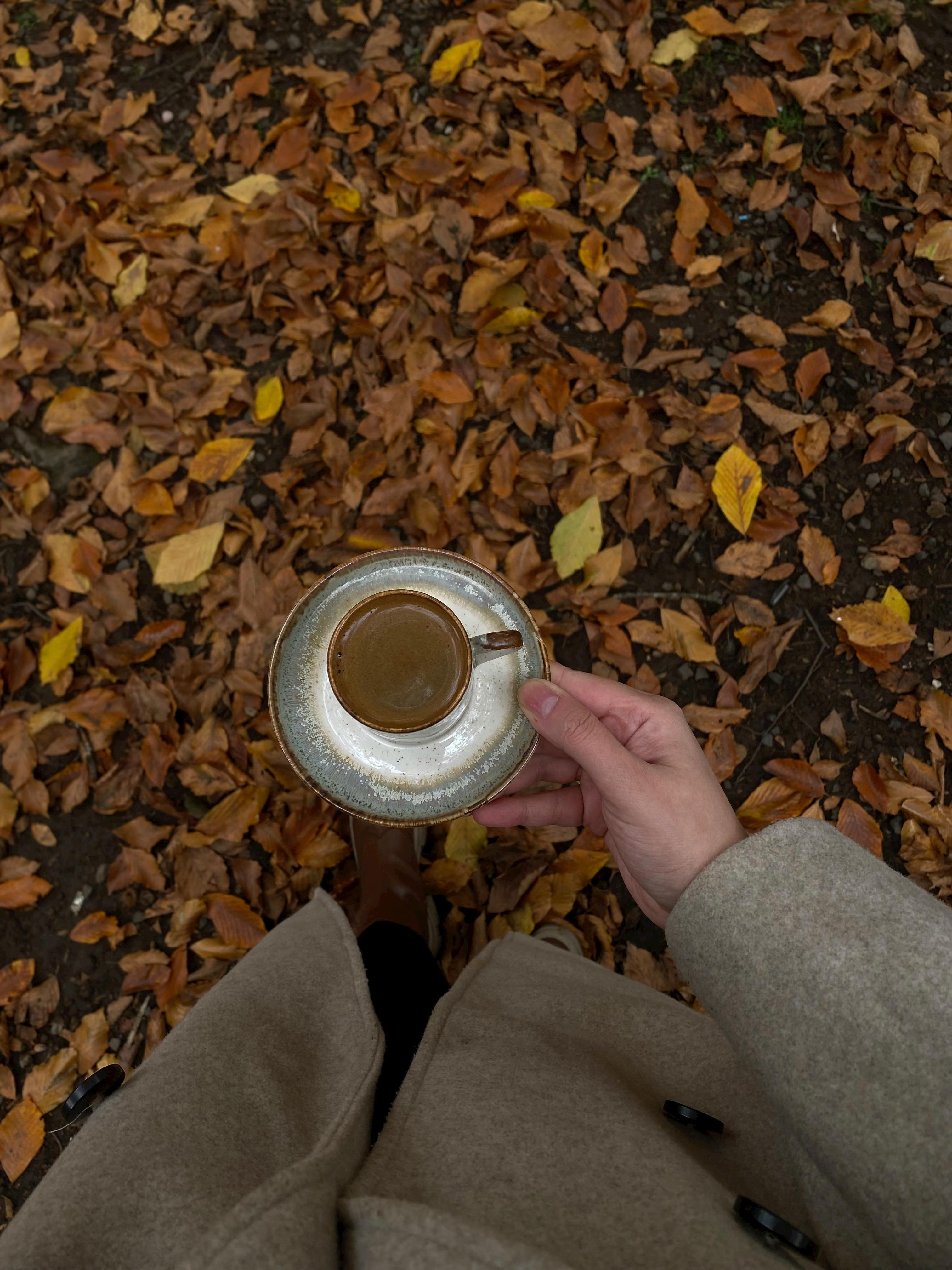 a person in a coat holding a cup of coffee