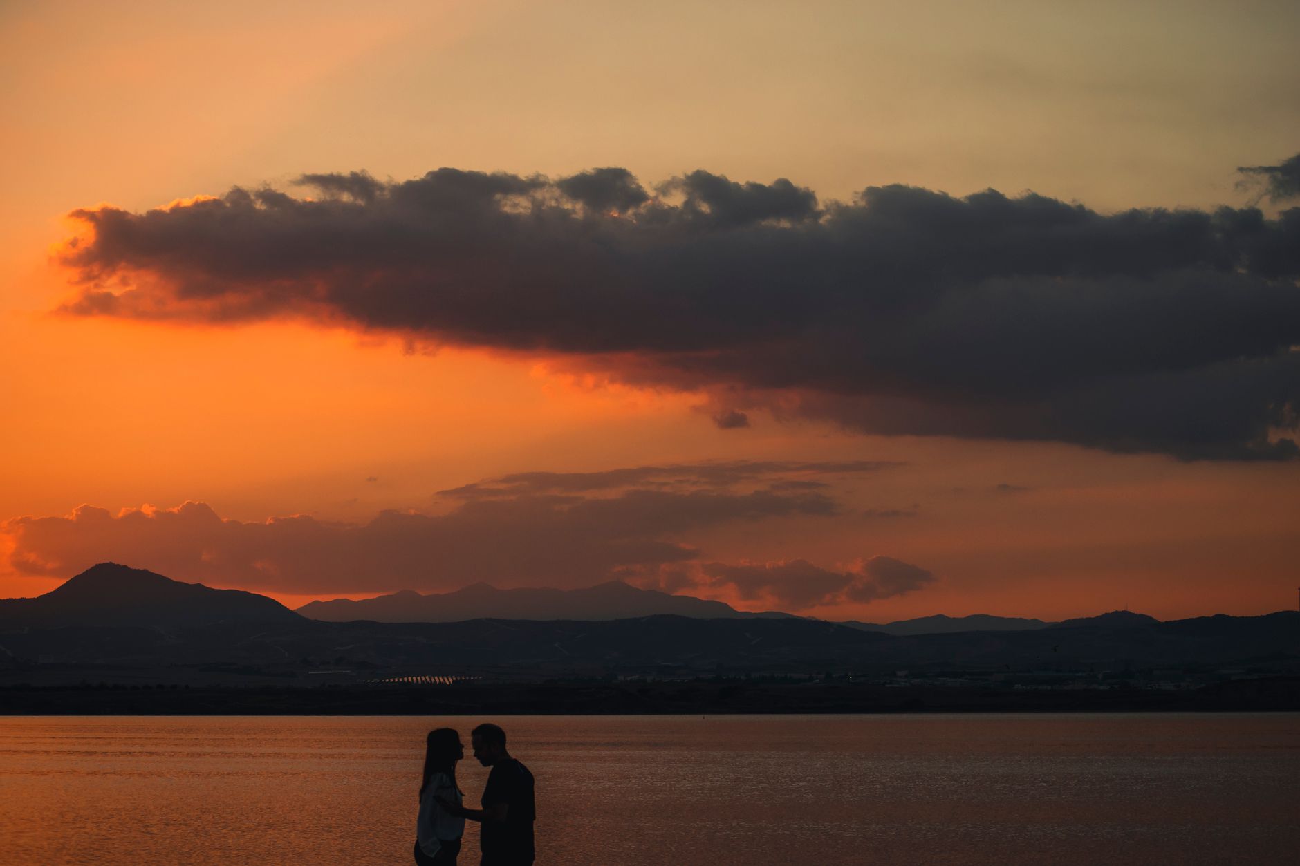 A couple shares a romantic moment during a stunning sunset at Larnaca Salt Lake, Cyprus. — photo by Ali Devecioglu / Pexels
