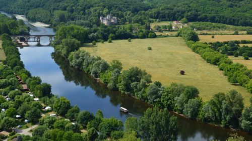 Free A scenic aerial view of a lush riverside landscape featuring a historic bridge and dense greenery. Stock Photo
