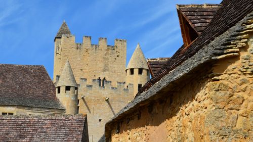 Free A beautiful medieval castle with stone towers and gothic architecture against a clear blue sky. Stock Photo