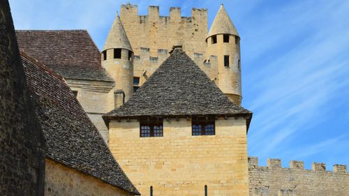 Free Close-up of a historic medieval stone fortress with distinct towers and battlements under a clear blue sky. Stock Photo