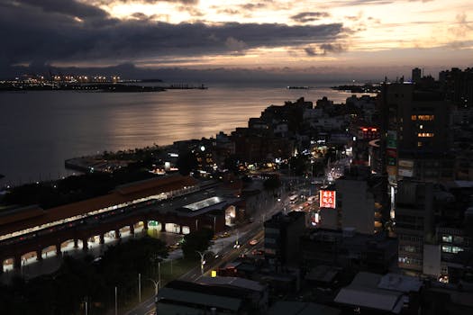 Aerial twilight view of New Taipei City with illuminated skyline and harbor.