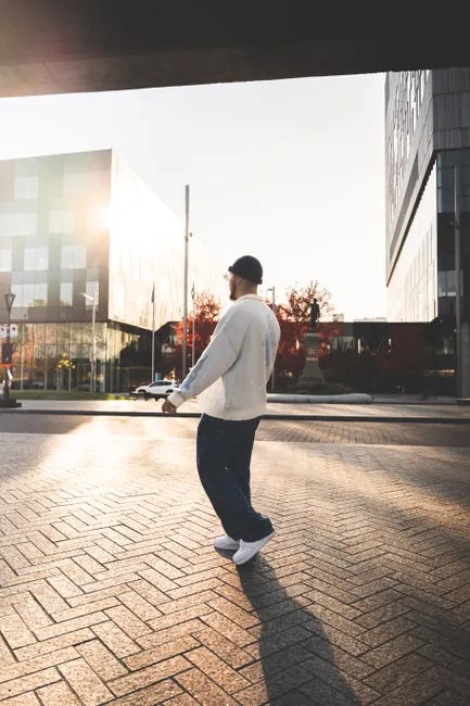 Homme en sweat oversize et bonnet se promenant en ville, look streetwear urbain hivernal