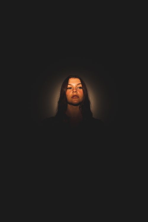 Free Dramatic portrait of a woman illuminated by a spotlight on a dark background for artistic effect. Stock Photo